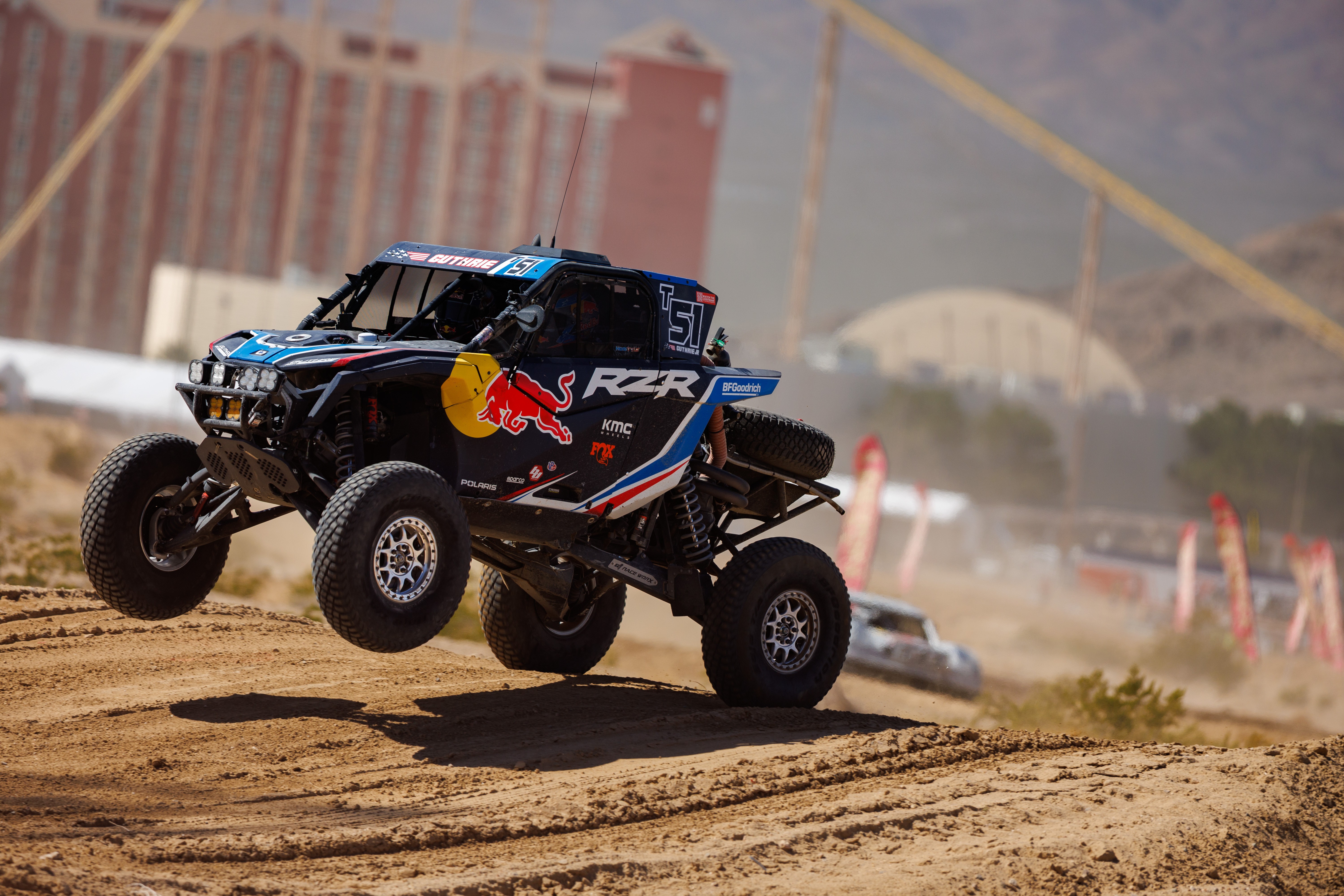 Car driving on a dirt road with Primm Valley Casino Resorts in the background